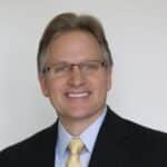 Professional financial advisor smiling in a suit and glasses.