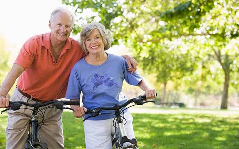 Senior couple enjoying outdoor bike ride in park.