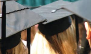 Graduates in caps and gowns celebrating at graduation ceremony.
