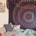 Dorm room decor with a large, intricate tapestry and plush pillows.