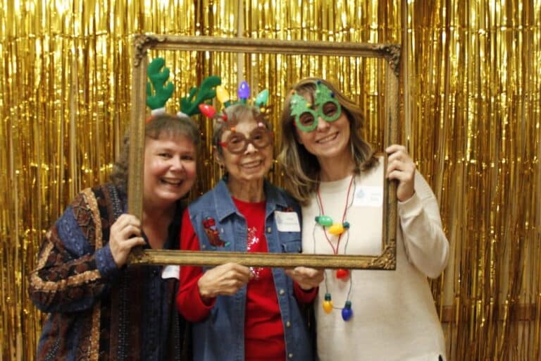 People celebrating Christmas with festive accessories and gold backdrop.