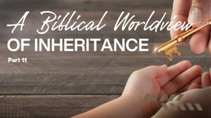 Hand passing a key symbolizing inheritance over a wooden table.